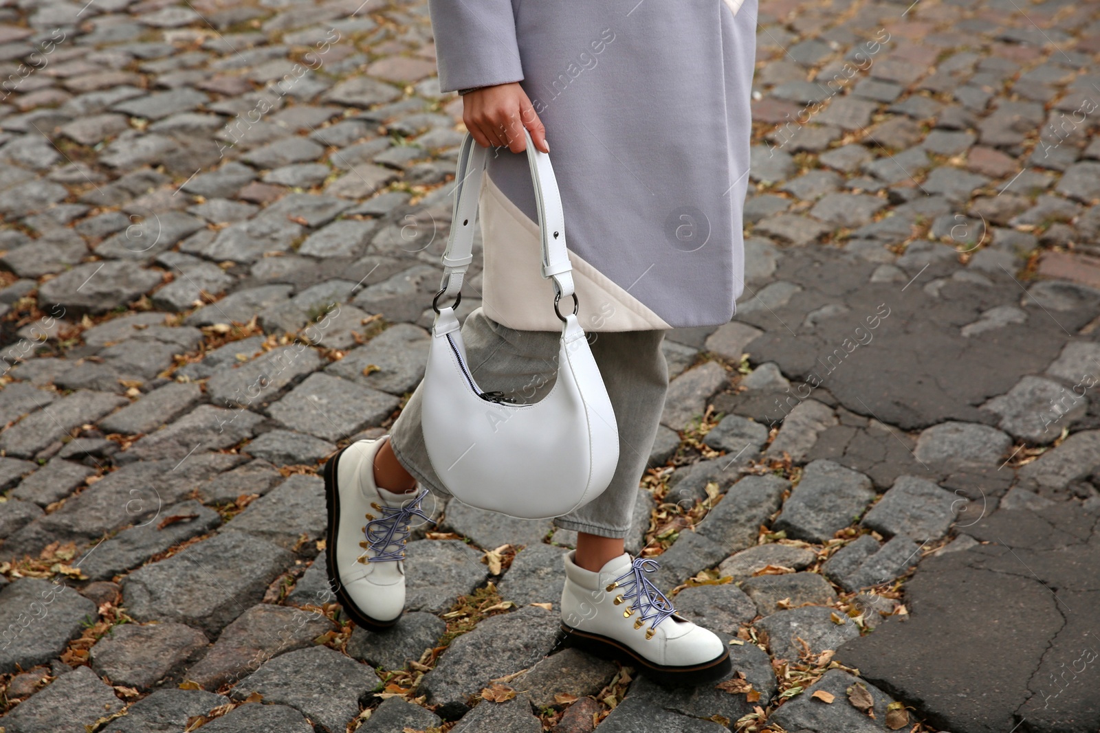 Photo of Stylish woman with trendy white baguette bag on city street, closeup