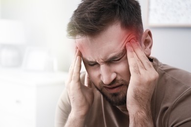 Image of Young man suffering from migraine at home, closeup