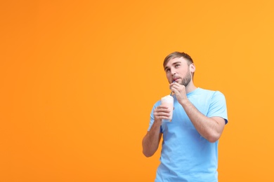 Photo of Young man with glass of delicious milk shake on color background