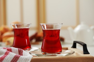 Glasses of traditional Turkish tea on wooden tray indoors