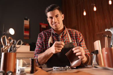 Man sewing piece of leather in workshop