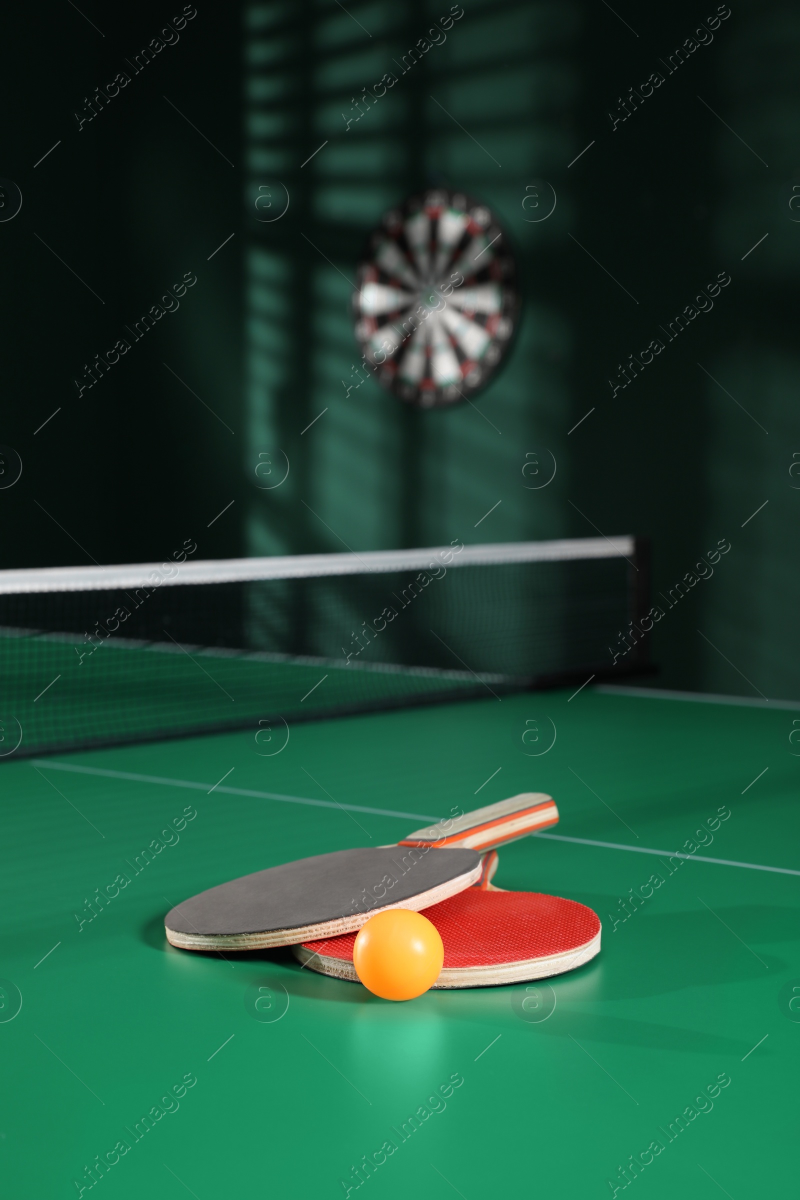 Photo of Rackets and ball on green ping pong table indoors. Space for text