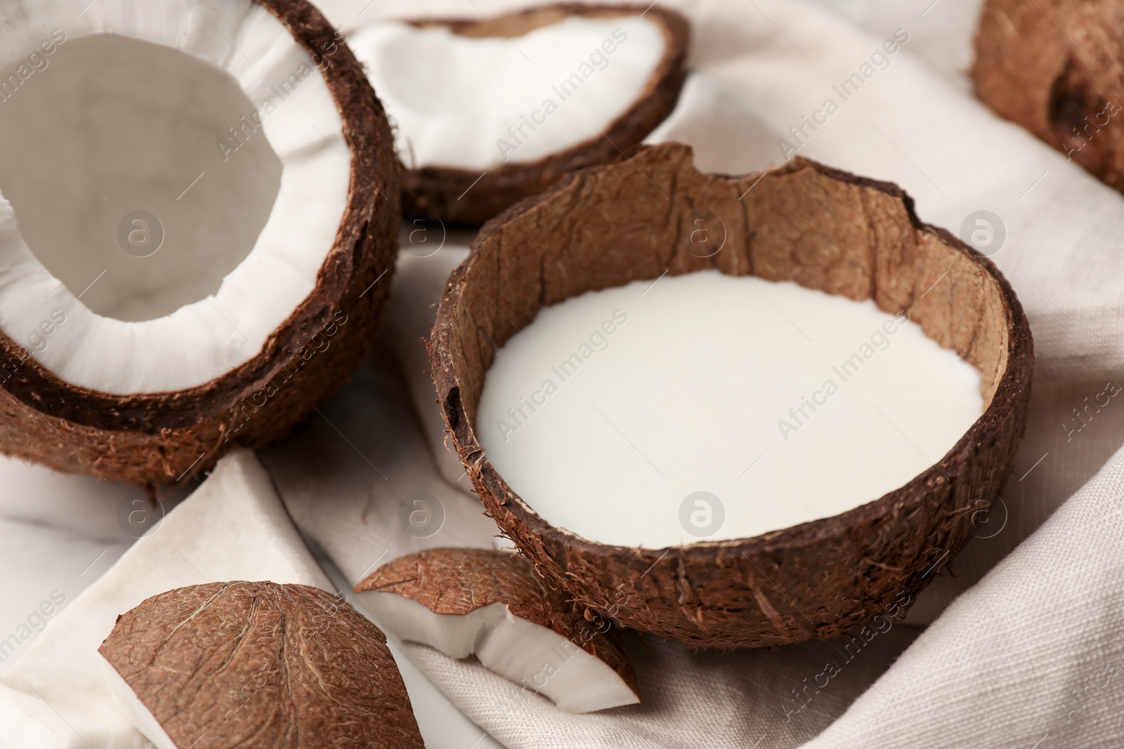 Photo of Delicious vegan milk in coconut and pieces of ripe fruit on white table, closeup