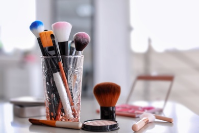 Holder with makeup brushes on table