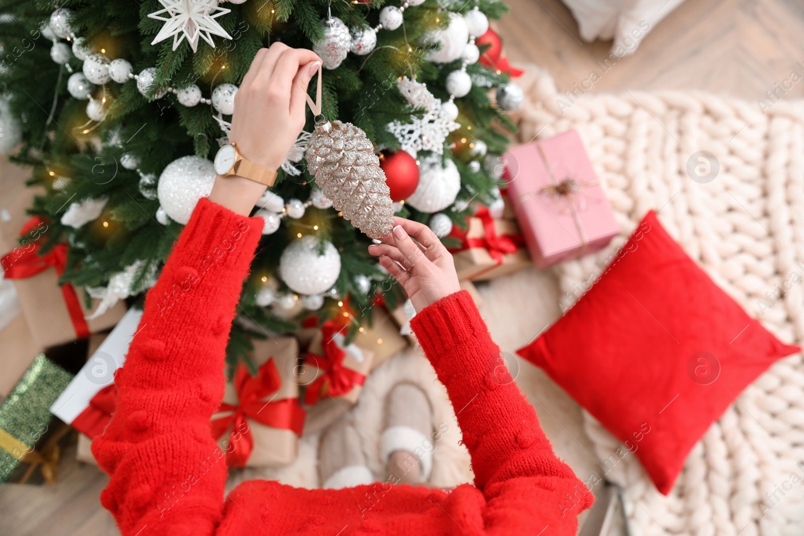 Photo of Woman decorating Christmas tree at home, top view