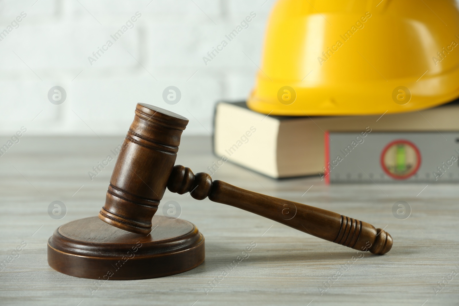 Photo of Construction and land law concepts. Judge gavel, protective helmet, ruler with book on wooden table