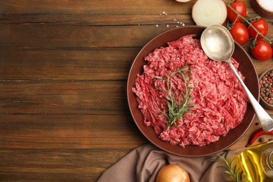 Photo of Fresh minced meat and other ingredients on wooden table, flat lay. Space for text