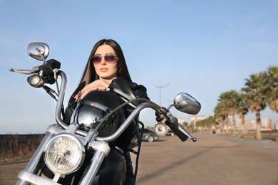Photo of Beautiful young woman with helmet sitting on motorcycle outdoors