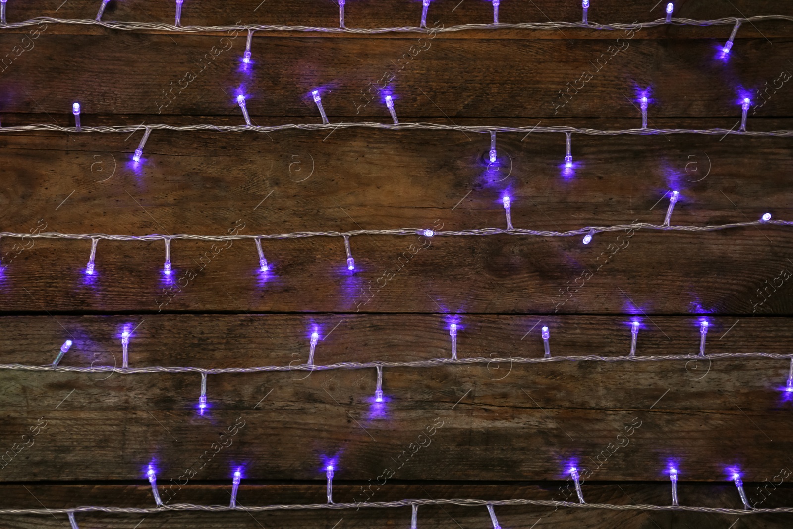 Photo of Blue Christmas lights on wooden background, top view