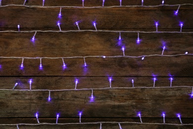 Blue Christmas lights on wooden background, top view