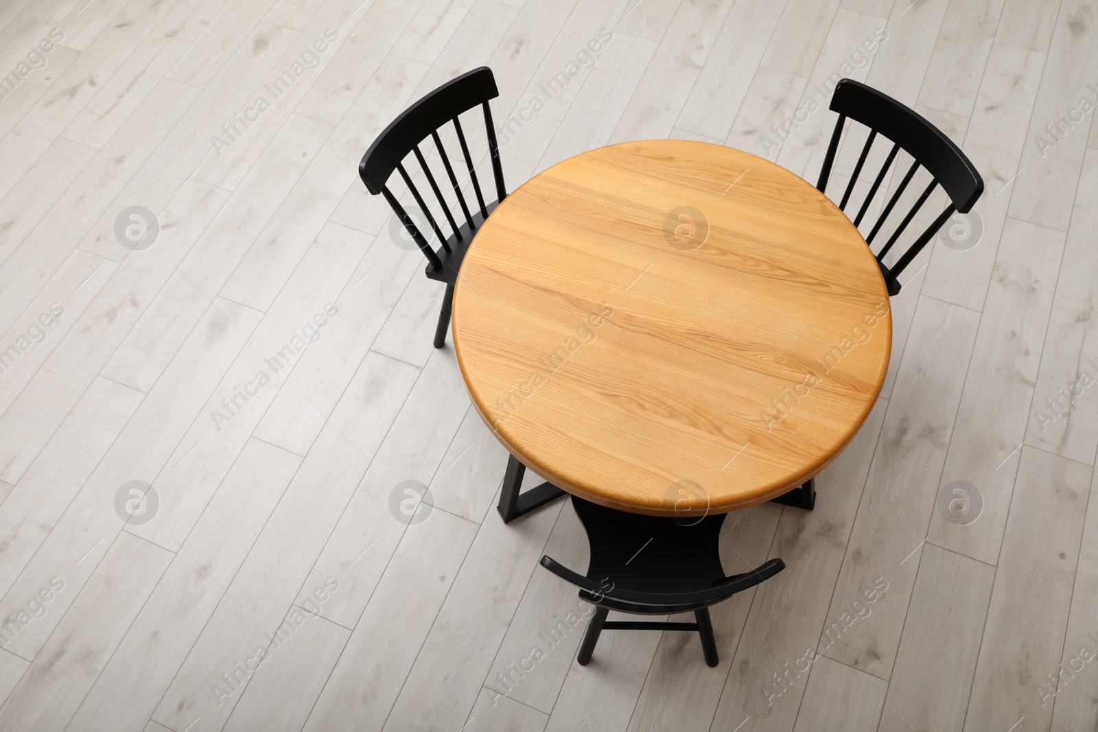 Photo of Stylish round table with black chairs on floor, above view