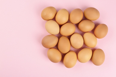 Raw chicken eggs on pink background, flat lay
