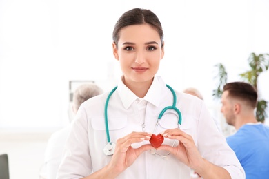 Photo of Female doctor holding small heart in clinic. Cardiology center