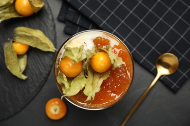 Photo of Delicious dessert decorated with physalis on black table, flat lay