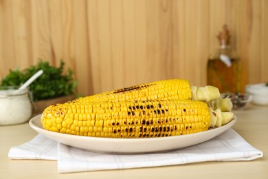 Photo of Plate with tasty grilled corn on wooden table