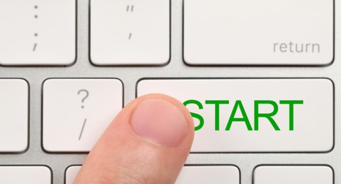 Image of Man pressing button with word Start on computer keyboard, closeup