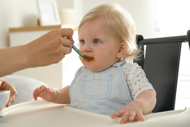 Mother feeding her cute little baby with healthy food at home