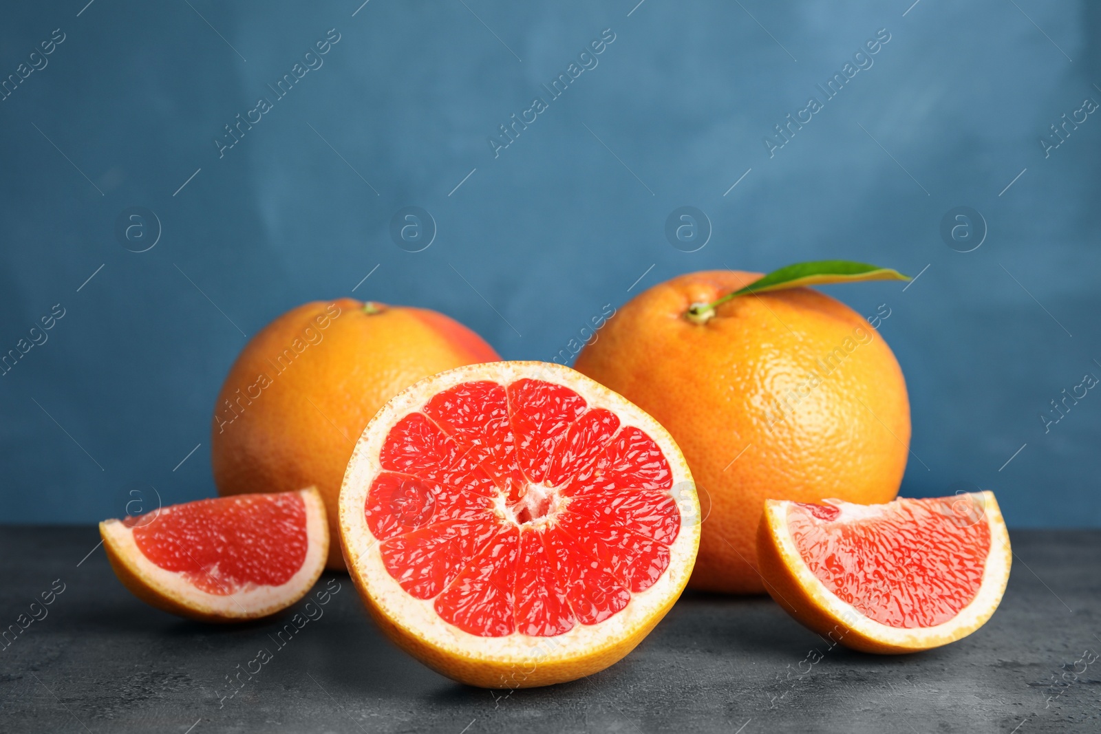 Photo of Fresh tasty grapefruits on table against color background