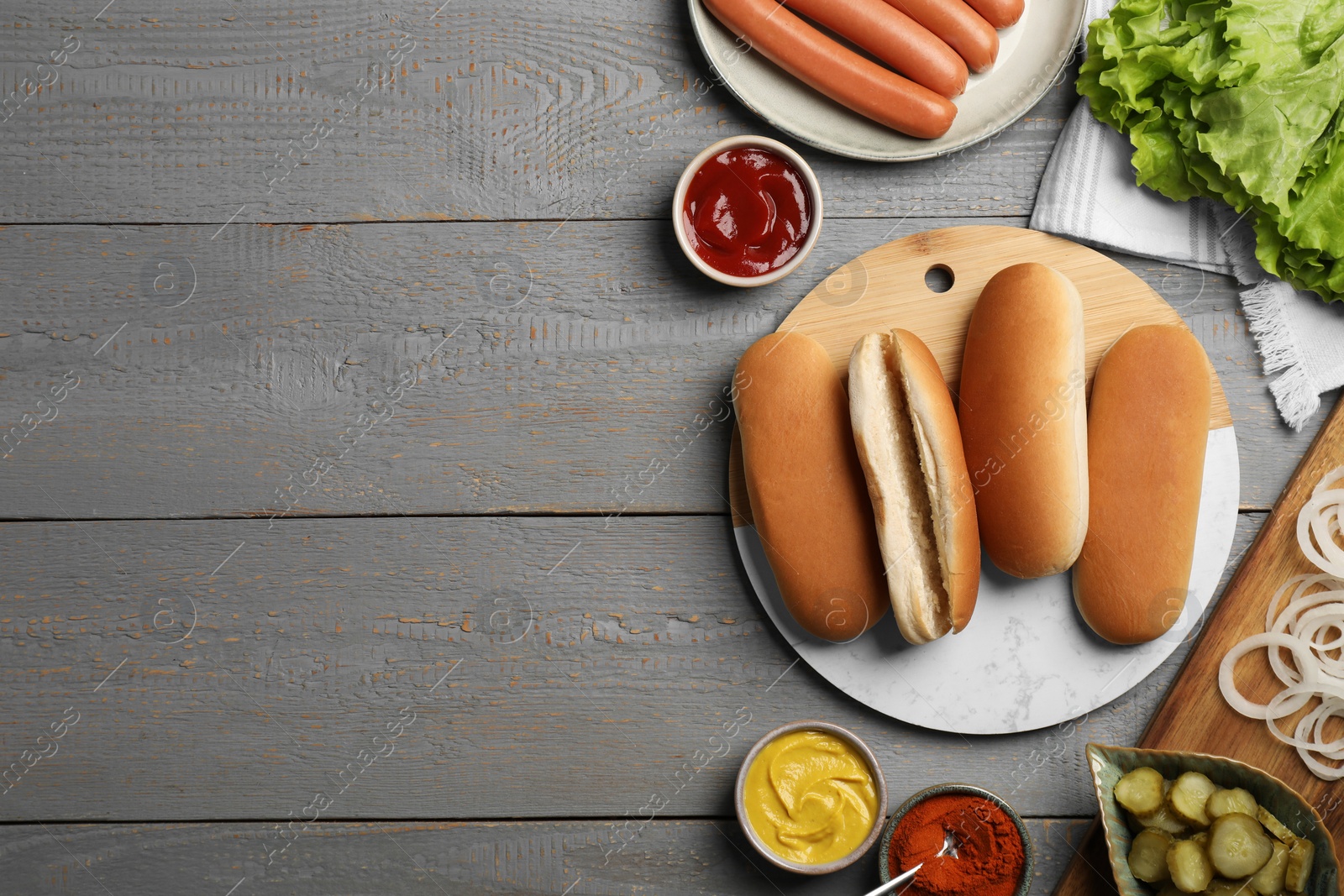 Photo of Different tasty ingredients for hot dog on light grey wooden table, flat lay. Space for text