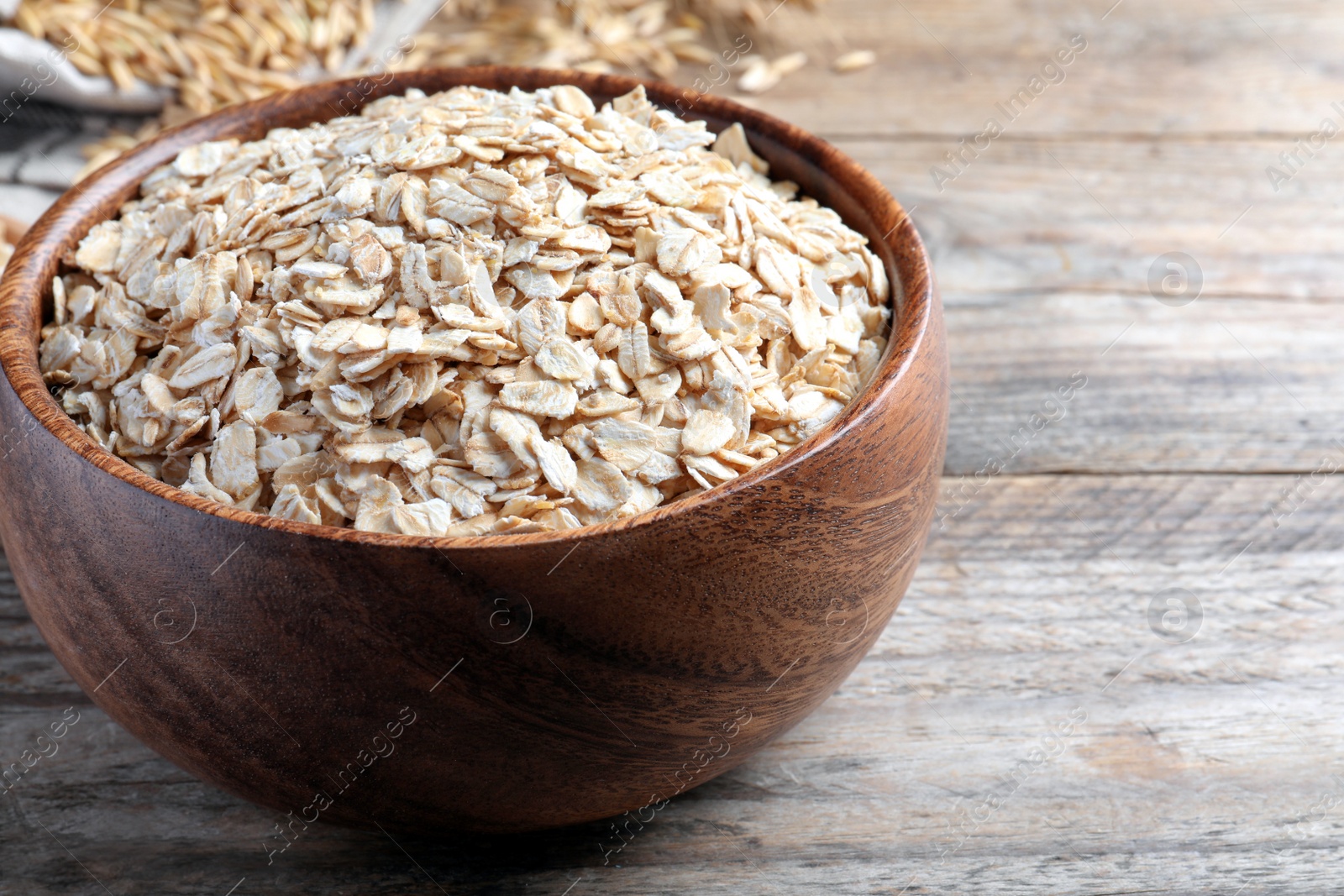 Photo of Bowl with raw oatmeal on wooden table. Space for text