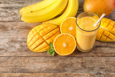 Photo of Tasty tropical drink with mango and fresh fruits on wooden table