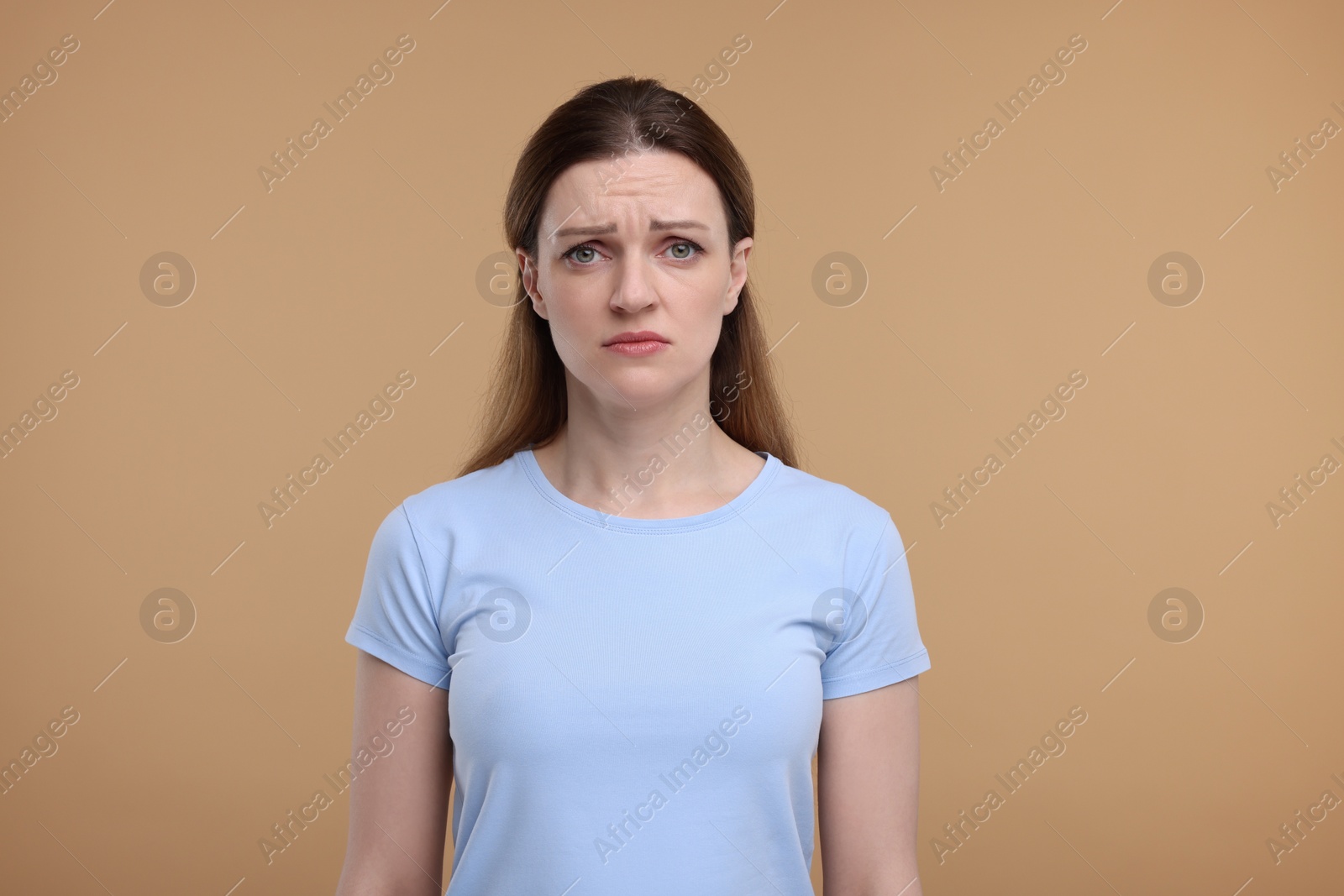 Photo of Portrait of sad woman on beige background