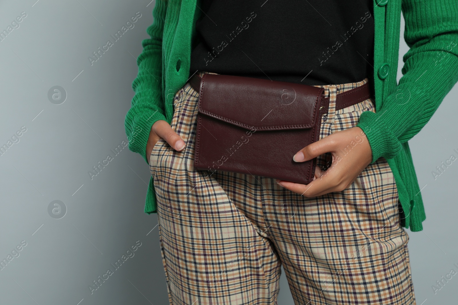 Photo of Young African American woman with stylish waist bag on grey background, closeup