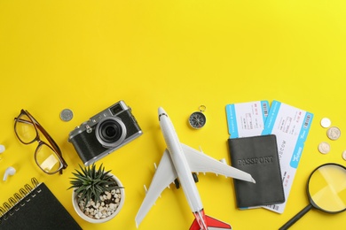 Photo of Flat lay composition with toy airplane and travel items on yellow background. Space for text