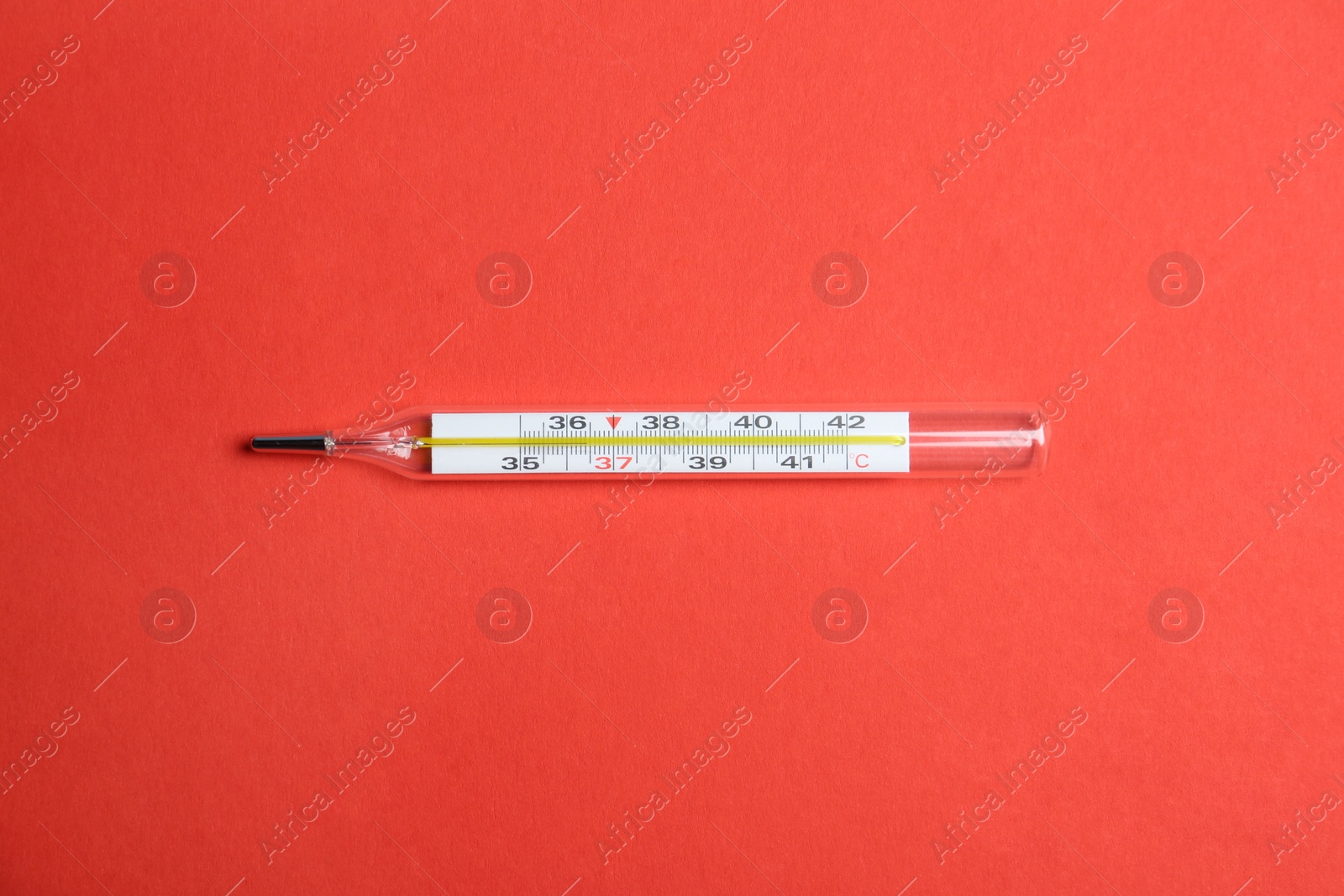 Photo of Mercury thermometer on red background, top view