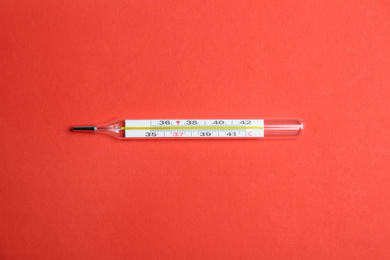 Photo of Mercury thermometer on red background, top view