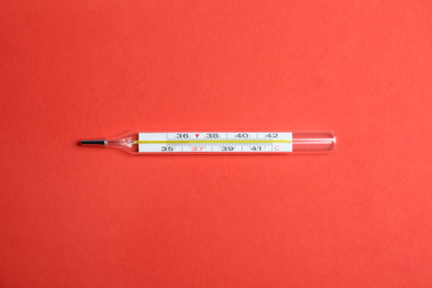 Mercury thermometer on red background, top view