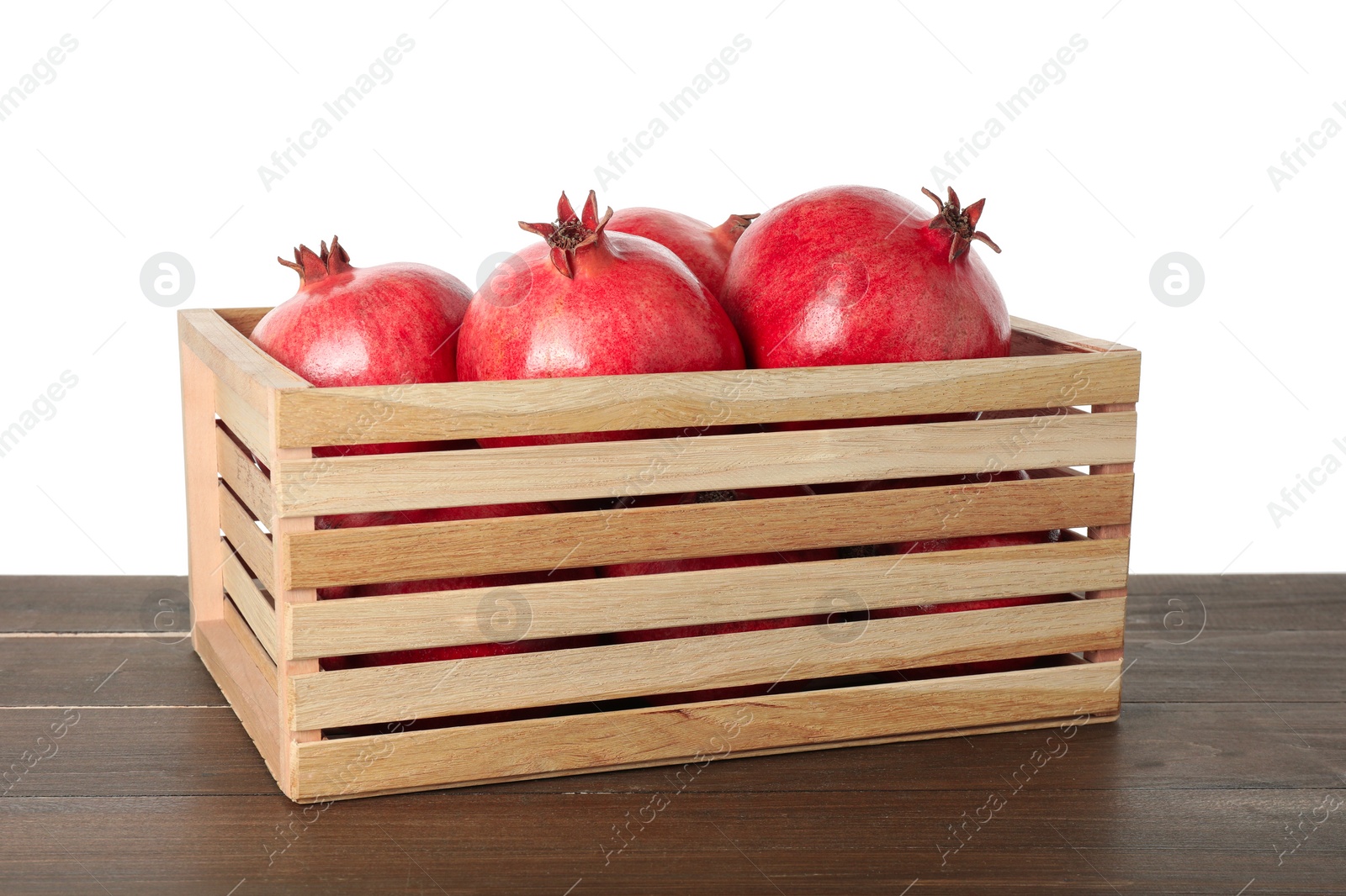 Photo of Fresh pomegranates in crate on wooden table against white background