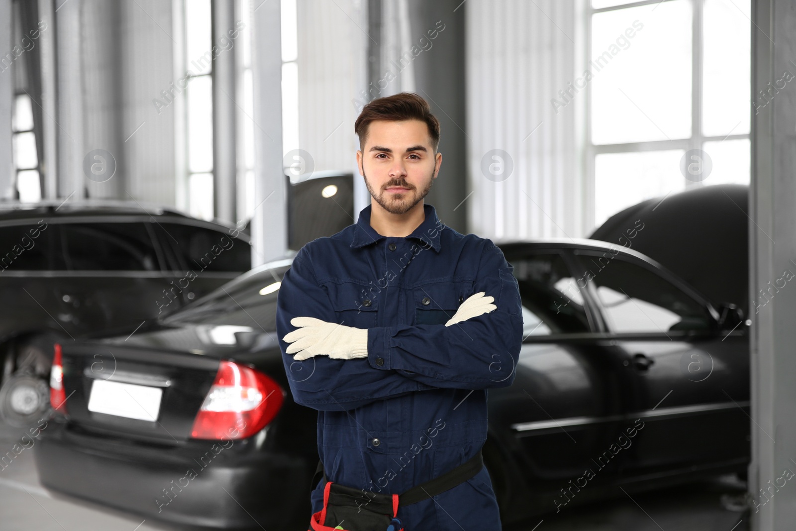 Photo of Portrait of technician near car at automobile repair shop