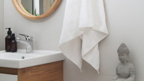 Photo of Hanging towel, sink and toiletries in bathroom. Interior design