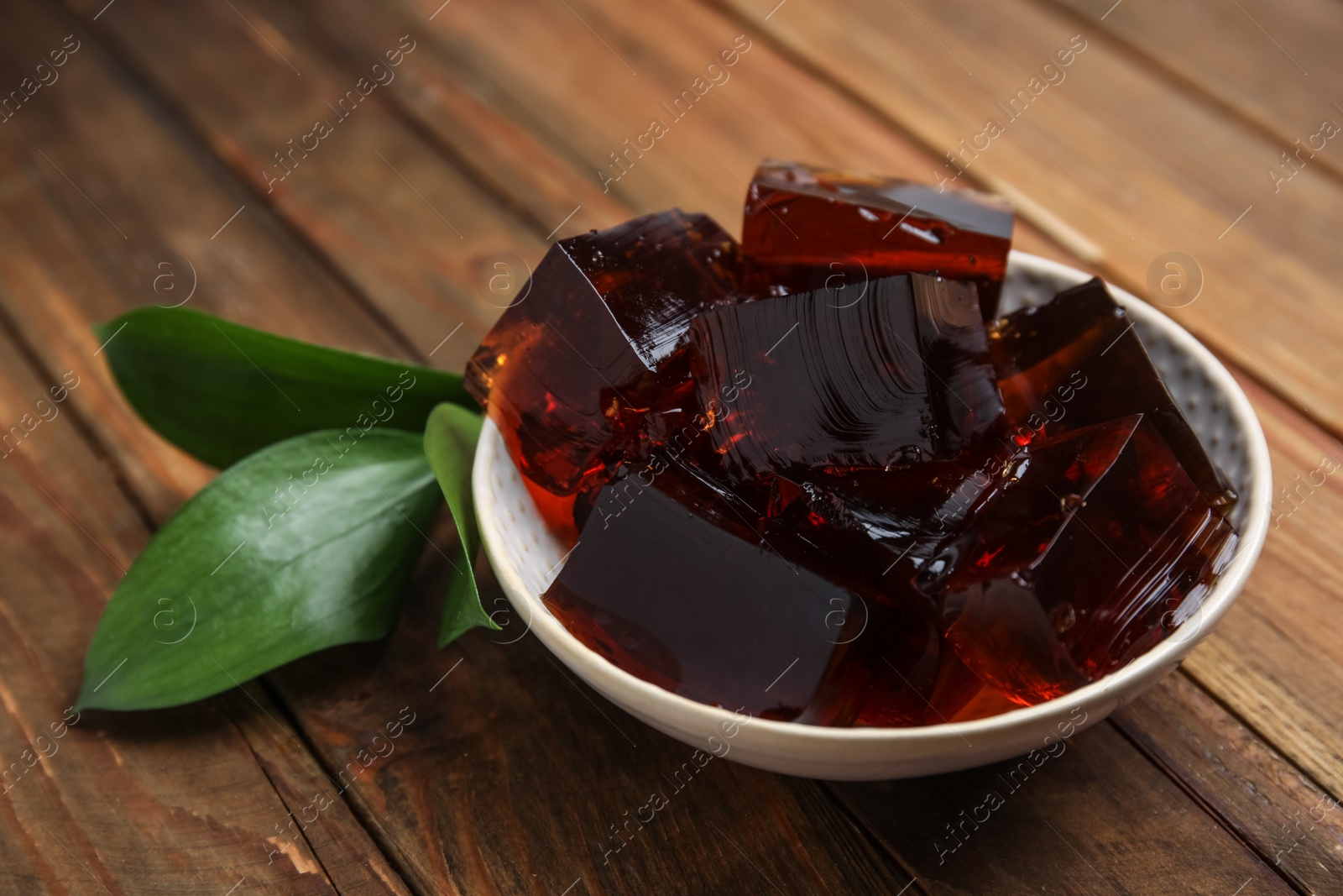 Photo of Delicious grass jelly cubes on wooden table, closeup