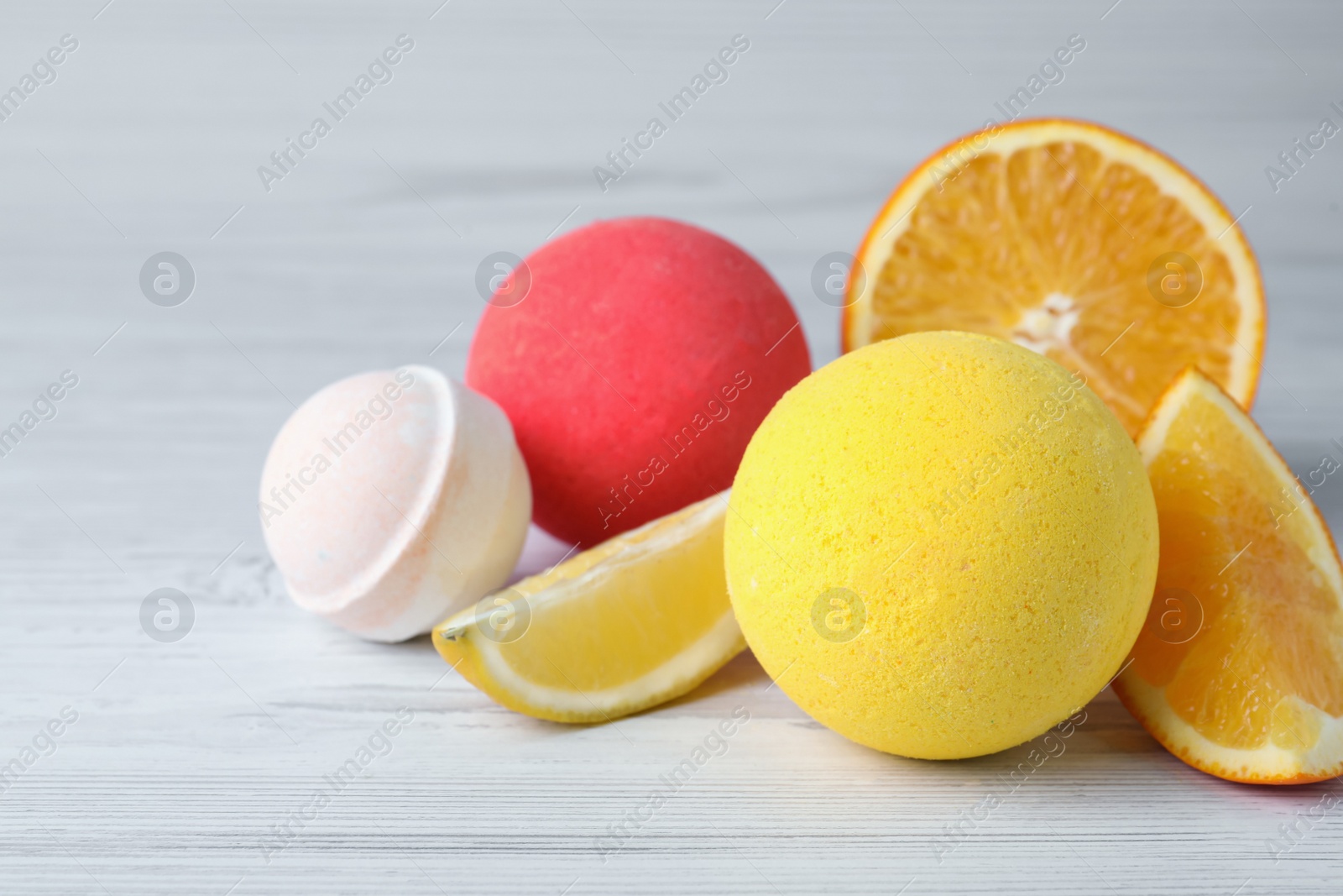 Photo of Citrus bath bombs and fresh orange on white wooden table