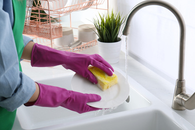 Photo of Woman washing plate in modern kitchen, closeup