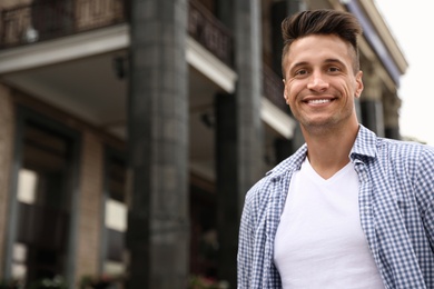 Photo of Portrait of handsome young man on city street. Space for text