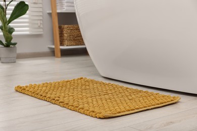 Photo of Soft yellow bath mat on floor in bathroom