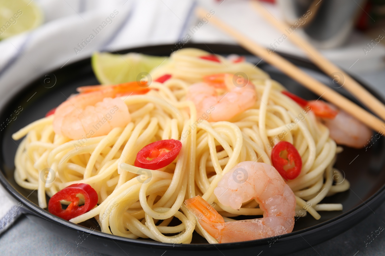 Photo of Tasty spaghetti with shrimps and chili pepper on grey table, closeup