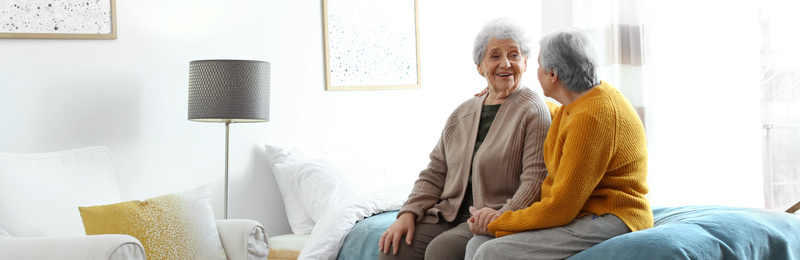 Image of Elderly women spending time together in bedroom, banner design. Senior people care