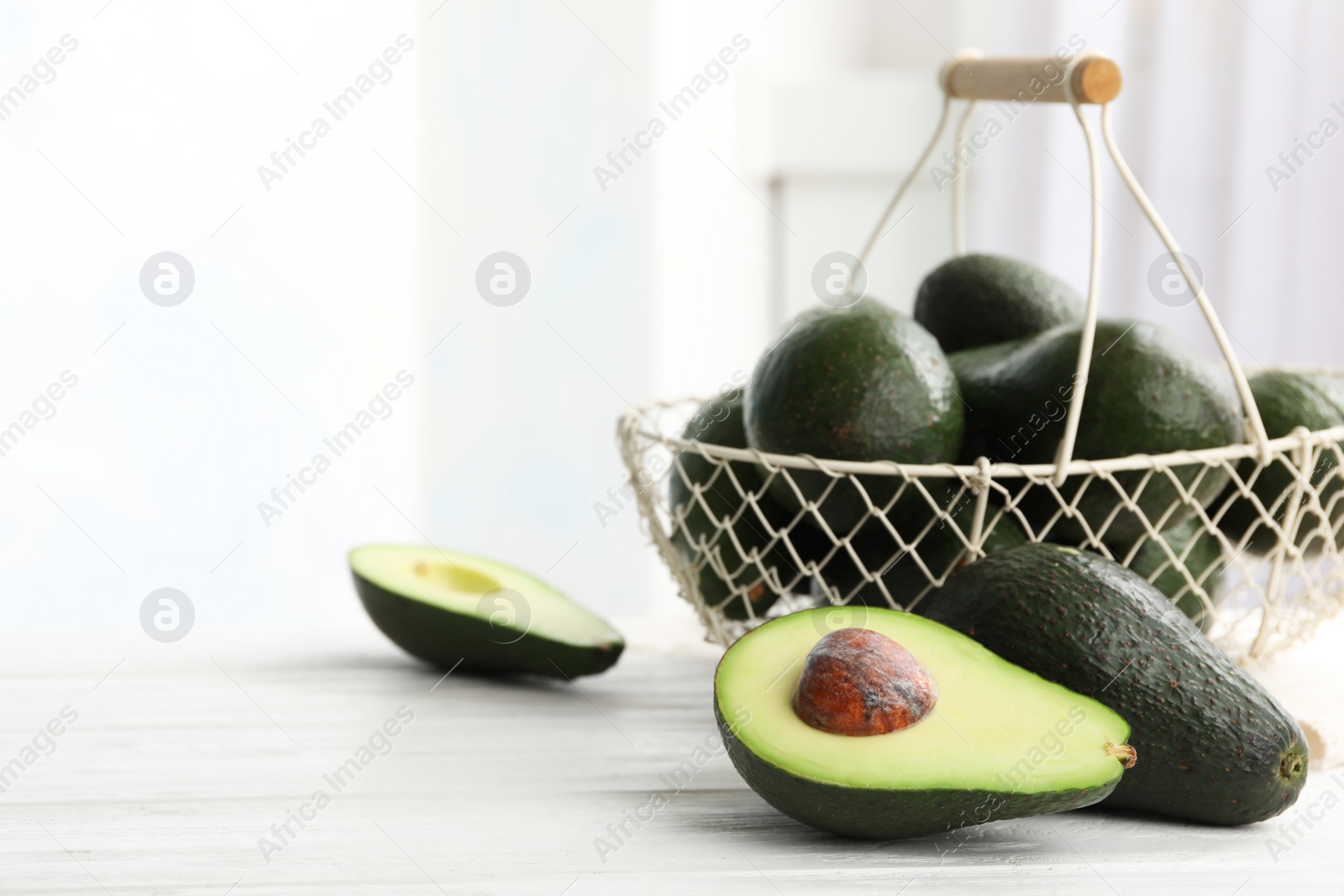 Photo of Delicious ripe avocados on white wooden table against light background