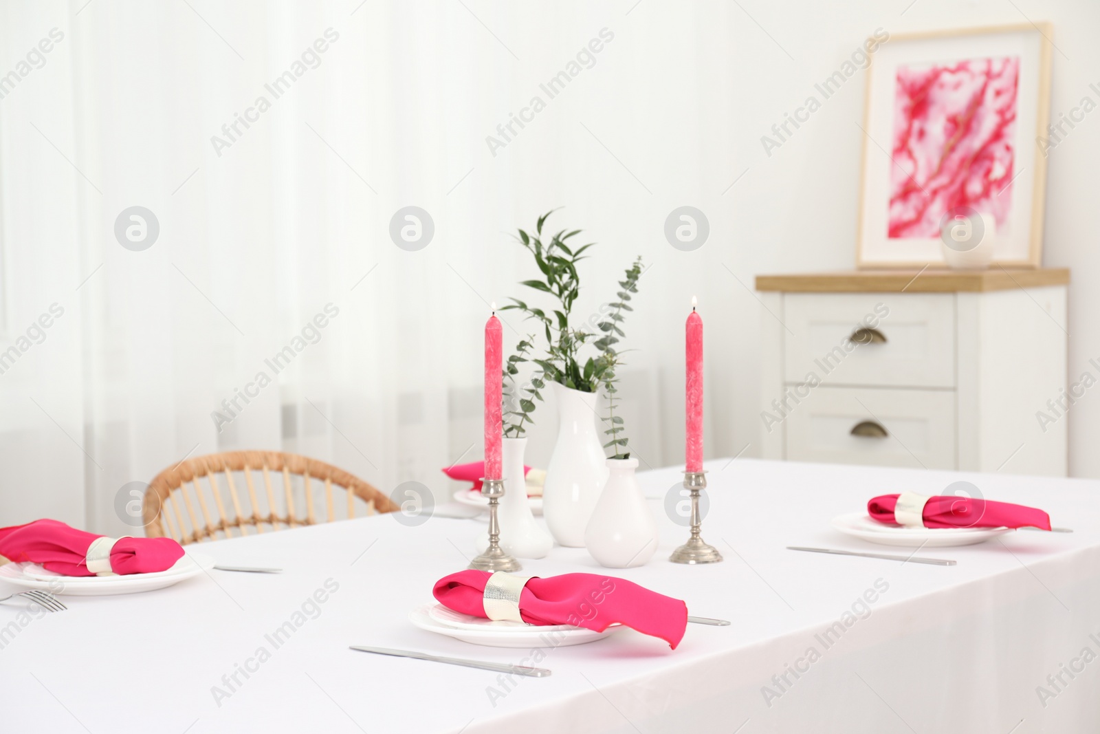 Photo of Beautiful table setting with green branches in vases and burning candles in dining room