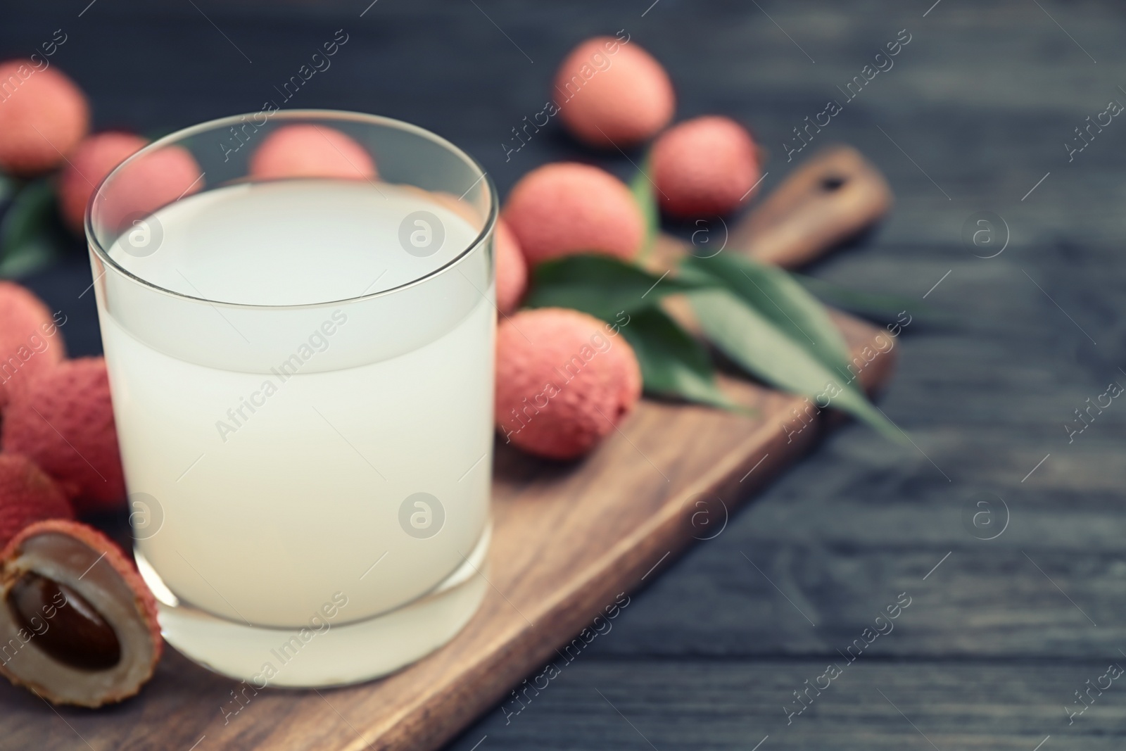 Photo of Fresh lychee juice on black wooden table. Space for text