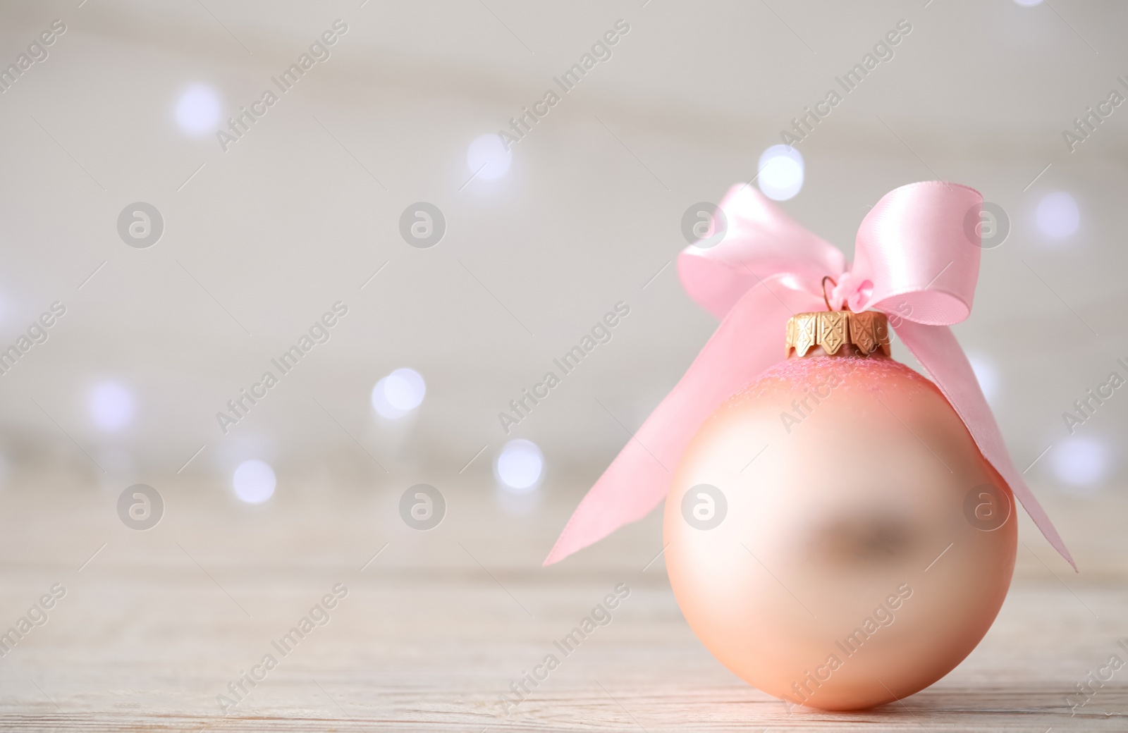 Photo of Beautiful Christmas ball on table against blurred festive lights. Space for text