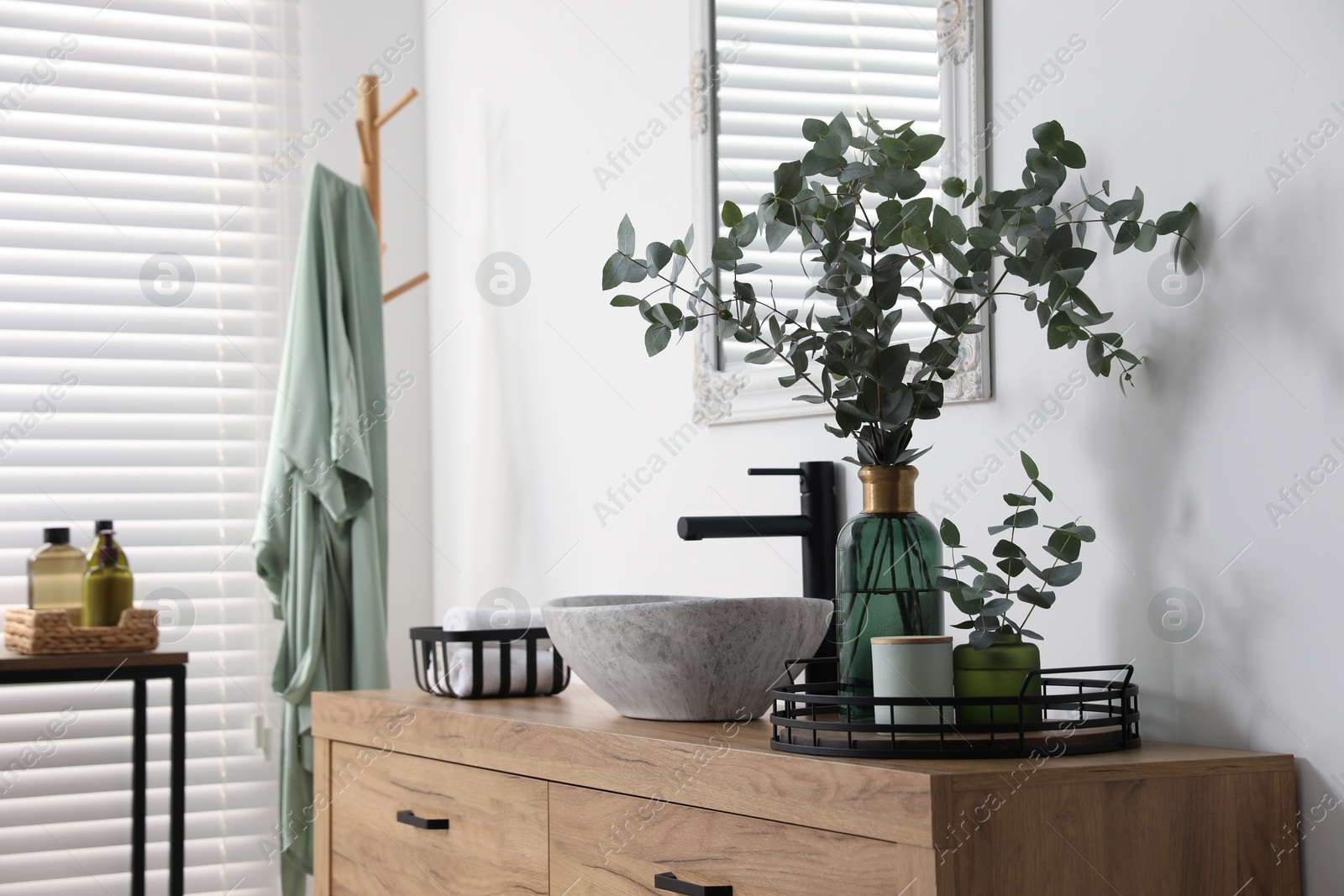 Photo of Beautiful eucalyptus branches near vessel sink on bathroom vanity. Interior design