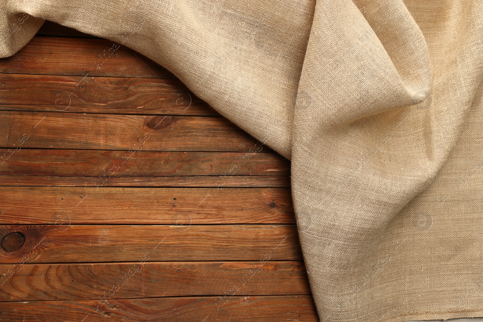 Photo of Burlap fabric on wooden table, top view. Space for text