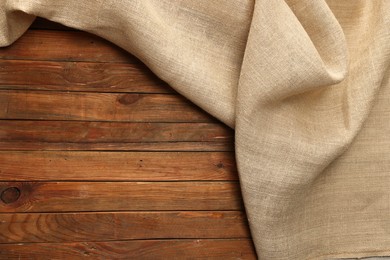 Burlap fabric on wooden table, top view. Space for text