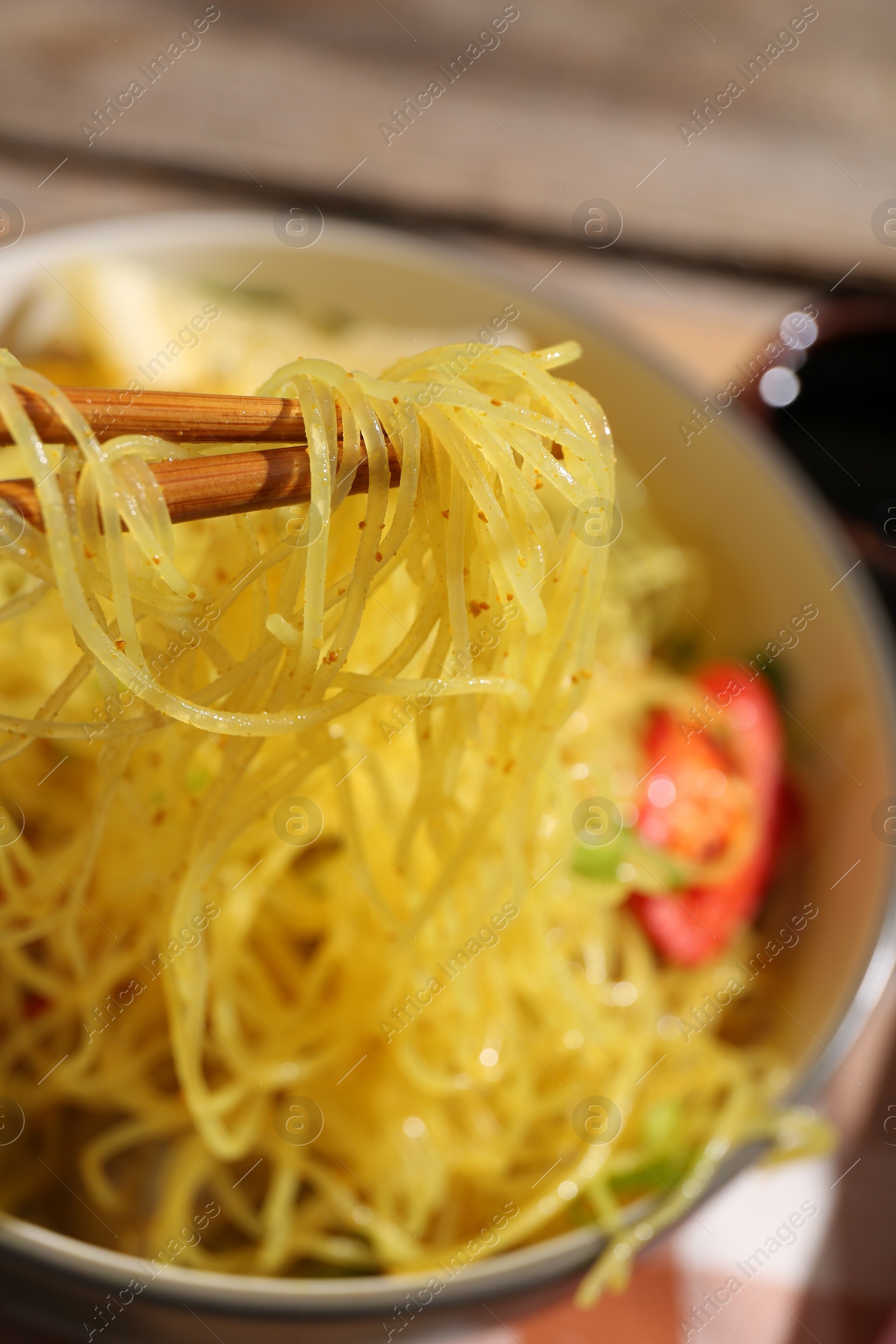 Photo of Stir-fry. Eating tasty noodles with chopsticks at table, closeup