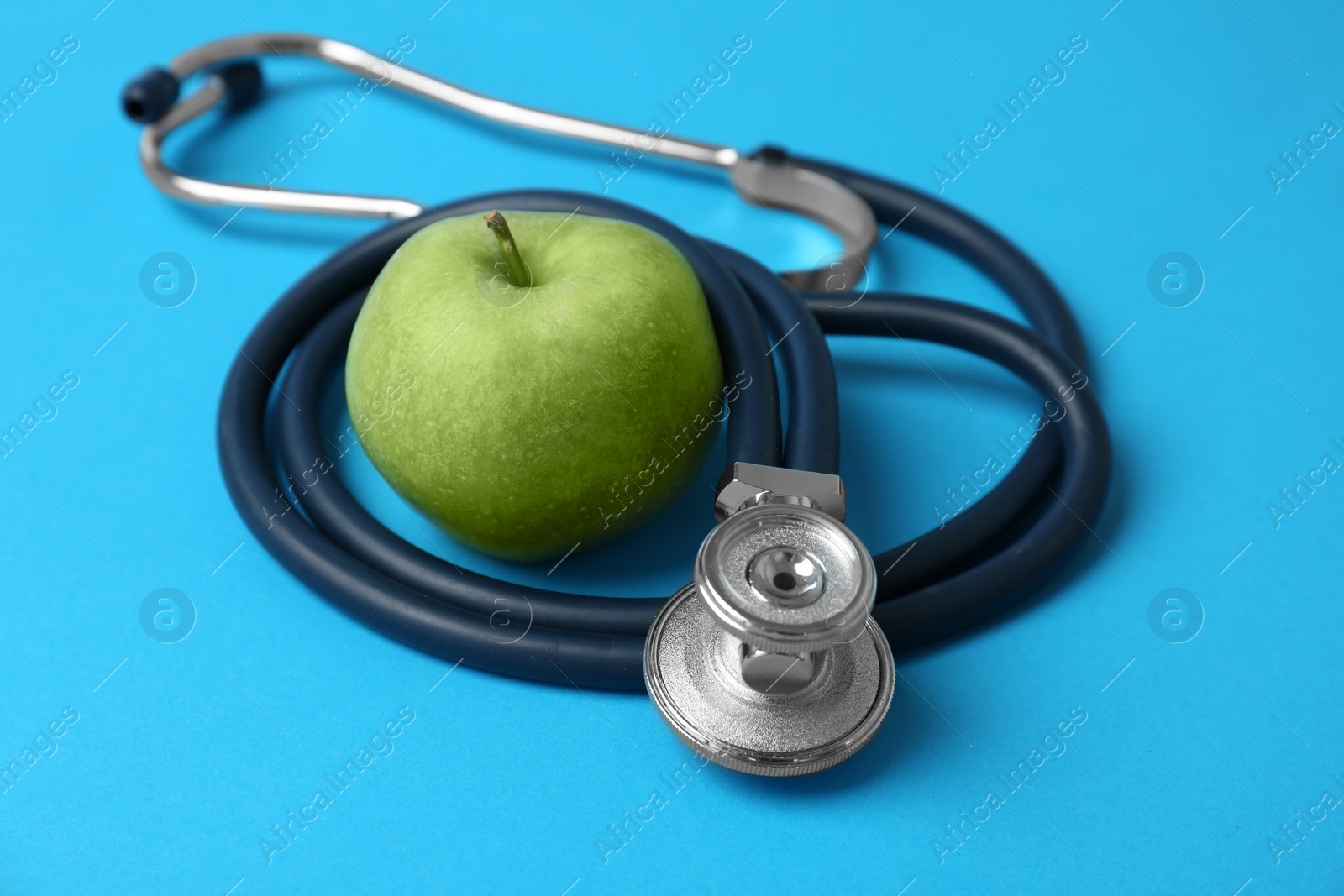 Photo of Stethoscope and apple on color background. Medical equipment